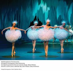 four ballerinas in pink tutu skirts and white headdress are dancing on stage