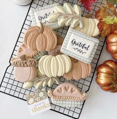 decorated cookies sitting on top of a cooling rack next to fall leaves and pumpkins