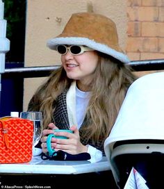 a woman wearing sunglasses and a hat sitting at a table