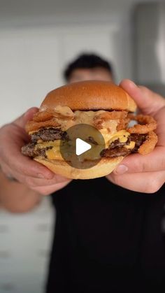 a man holding up a hamburger in his hands