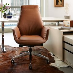 a brown leather office chair sitting on top of a cowhide rug