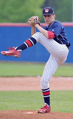 a baseball player pitching a ball on top of a field with his leg in the air