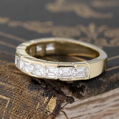 a close up of a wedding ring on top of a piece of wood with an old book in the background