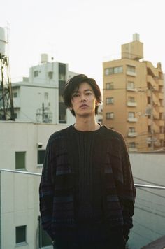 a young man standing on top of a roof next to tall buildings in the city