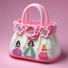 a crocheted purse with princesses on it and flowers in the center, sitting on a pink surface