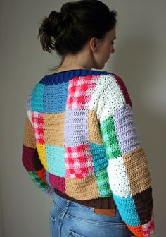 a woman wearing a multicolored crochet sweater and jeans, back view