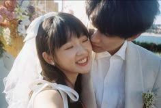 a bride and groom kissing each other outside