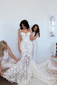 three women in white dresses are posing for the camera and one woman is holding her dress