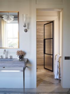 a bathroom sink sitting under a mirror next to a doorway