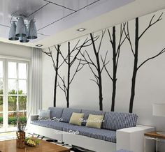 a living room with white walls and black trees on the wall, along with blue couches