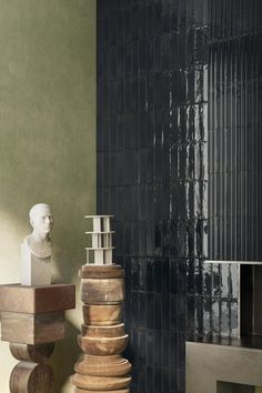 three wooden sculptures sitting next to each other in front of a wall with black tiles on it