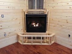 a fire place in the corner of a room with wood flooring and white walls