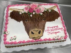 a birthday cake decorated with a cow's head and flowers