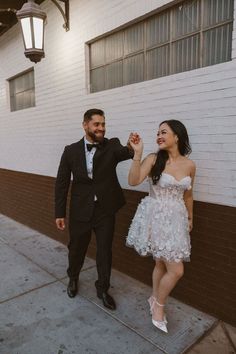 a man in a tuxedo and a woman in a white dress hold hands