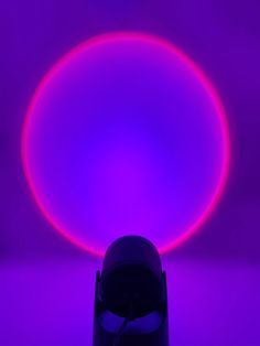 a light that is on in the middle of a purple room with a round object behind it