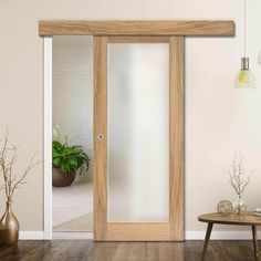 an empty room with a wooden door and some plants on the table next to it