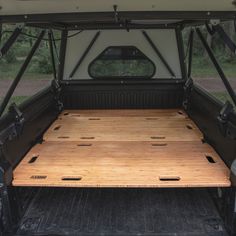 the back end of a pickup truck with wood flooring in the cargo area and open doors