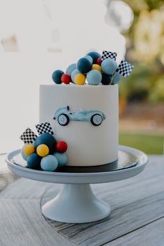 a white cake with blue, yellow and red decorations sitting on top of a table