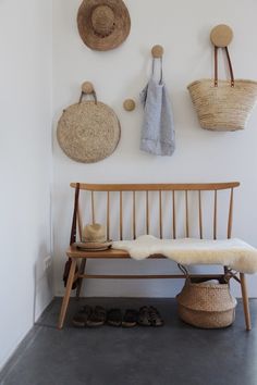 a wooden bench sitting next to a wall with baskets hanging on it's side