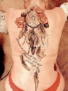 the back of a woman's body with flowers and feathers tattooed on her stomach