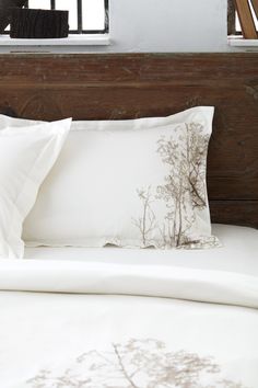 a bed with white sheets and pillows in front of a window