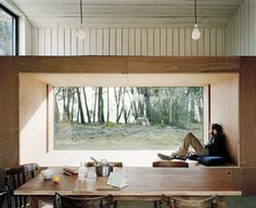 a person sitting at a table in front of a window with the view of trees outside