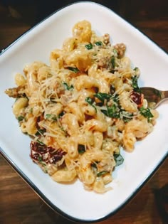 a white plate topped with pasta covered in cheese and spinach next to a fork