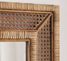 a close up of a mirror on a wall with a rattan frame and pattern