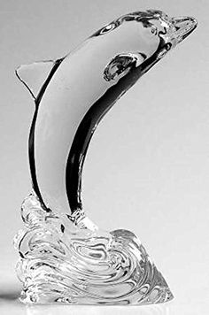 a glass dolphin figurine sitting on top of a white countertop next to a black and white background