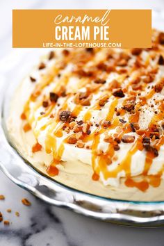 a cake with caramel cream and pecans on top sitting on a glass plate