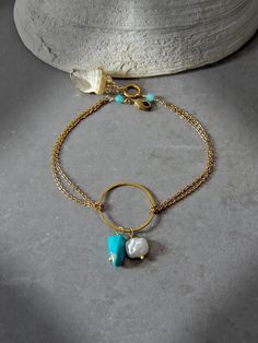 Capture the impactful symbology of natural gemstones with this dainty chain artisan circle bracelet. Adorned with a single natural freshwater keshi pearl, genuine Arizona Sleeping Beauty turquoise, micro faceted amazonite rounds & a gold accented natural shell pendant, this intentional bracelet reflects the symboli Dainty 14k Gold Filled Circular Jewelry, Turquoise Round Gold-plated Jewelry, Turquoise Gold-plated Round Jewelry, Minimalist Jewelry With Natural Stones, Minimalist Round Natural Stone Jewelry, Gold Bohemian Pearl Bracelet With Gemstone Beads, Bohemian Gold Pearl Bracelet With Gemstone Beads, Dainty Turquoise Gold-plated Jewelry, Gold Bohemian Jewelry With Pearl Charm