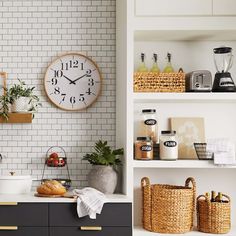 a clock mounted to the side of a white brick wall above a kitchen counter top