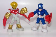 two toy action figures are posed on a white surface