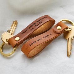 two personalized leather keychains with engraved words on them, one is brown and the other is gold