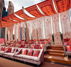 an outdoor seating area with red and orange pillows on the couches next to stairs