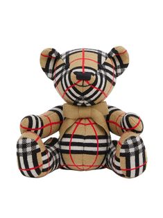 a brown teddy bear sitting on top of a white surface with black and red stripes