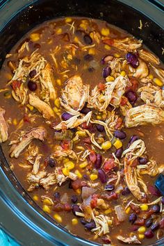 a crock pot filled with chicken, beans and corn on top of a blue towel