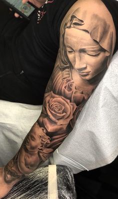 a man with a black and grey tattoo on his arm is holding a white rose