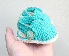 a hand holding a small crocheted baby shoe