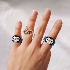 a woman's hand with two rings and an owl beaded ring on it