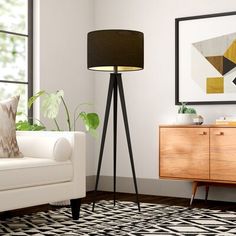 a living room with a white couch, black and gold lamps and a rug on the floor