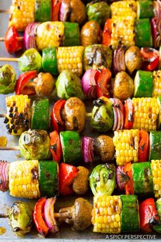 corn on the cob and vegetable skewers are ready to be grilled