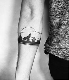 a man's arm with a wolf tattoo on it and the moon in the background