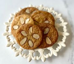 three cookies with almonds are on a white plate