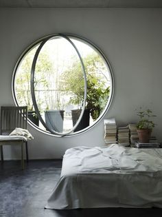 a bed sitting under a round window in a bedroom