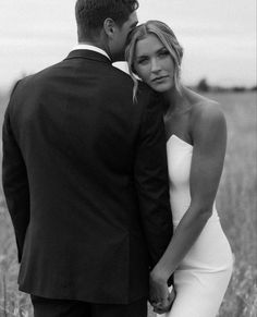 a bride and groom standing in the middle of a field