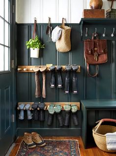 an entryway with green painted walls and lots of shoes hanging on the wall,