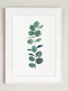 a green leaf print hanging on a wall next to a white framed frame with the words,