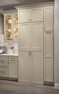 a kitchen with white cabinets and wood floors