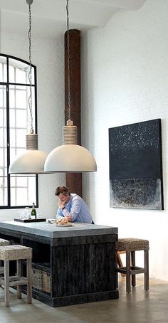 a man is sitting at a table in the middle of a room with large windows